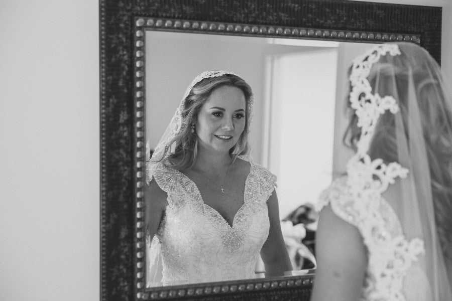 bride looking in mirror with mantilla veil