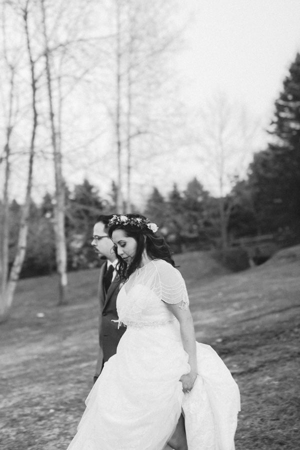 bride and groom walking through the woods black and white