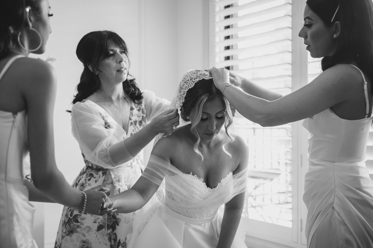 Bride putting on mantilla veil