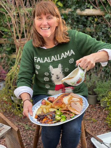 Louise pouring gravy on a Christmas dinner cooked in a fire pit