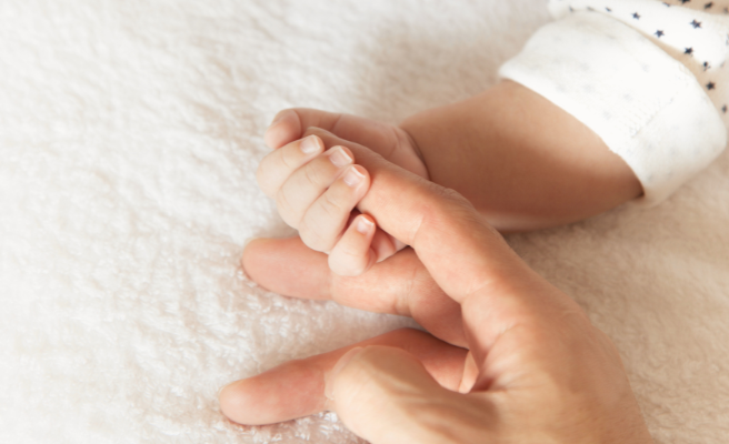 baby holding mom's finger