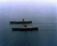 A port view of the aircraft carrier USS FORRESTAL (CV 59) steaming alongside the nuclear-powered aircraft carrier USS ENTERPRISE (CVN 65).<br>- 1989