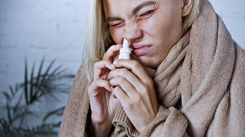 stock-photo-diseased-woman-covered-warm-blanket-frowning-while-using-nasal-spray.jpeg__PID:5d670671-dc53-4759-92c5-6312684efc86