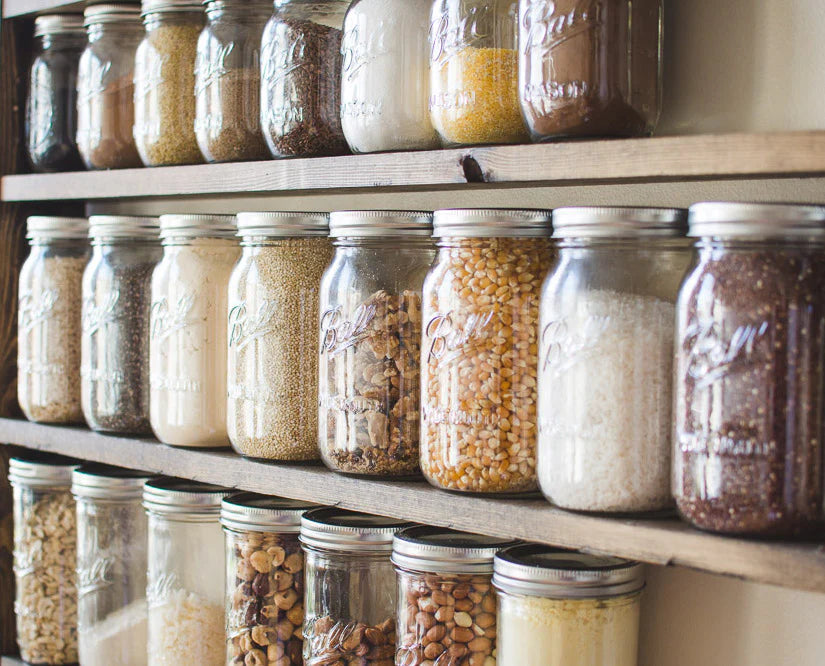 Rows of labeled glass jars filled with various dry goods on wooden shelves.