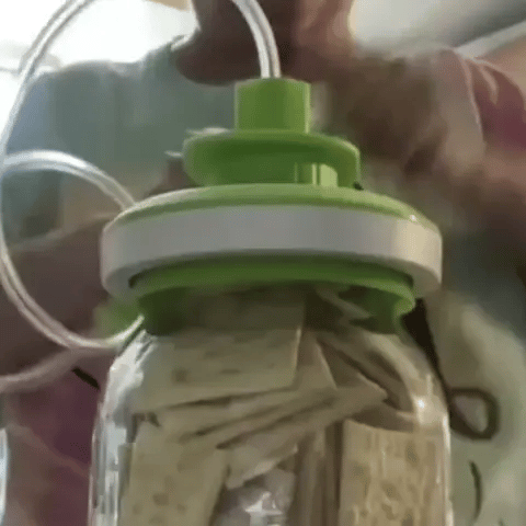 Person pouring noodles into a container with a green funnel.