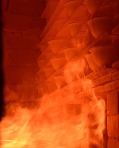 Woodfire kiln flames hitting ceramic bowls