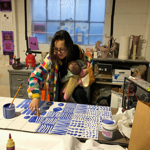 Jessie painting tiles with one month old baby Yuka in preparation for Ochre Bakery