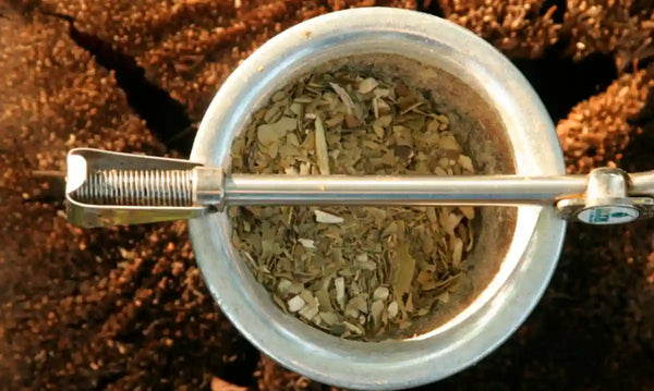 Mate con yerba en su interior y una bombilla cruzada arriba