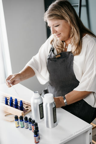 Sherrie Miller, Owner of Essential for Wellness, in a gray apron creating essential oil blends.