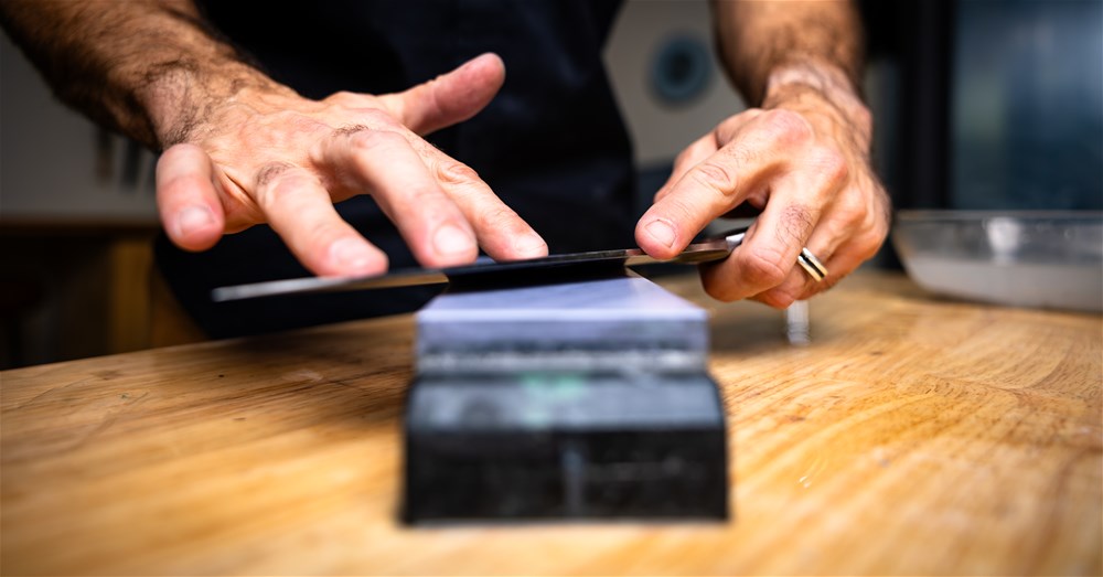 Image of a chef's knife being sharpening on a water stone