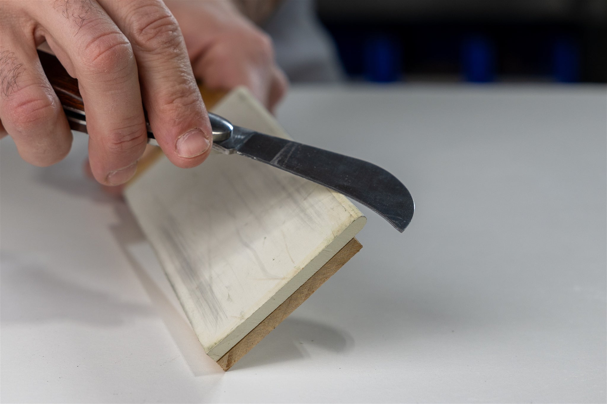 A curved knife being stropped on the profiled edge of the Wood Is Good Large Synthetic Strop