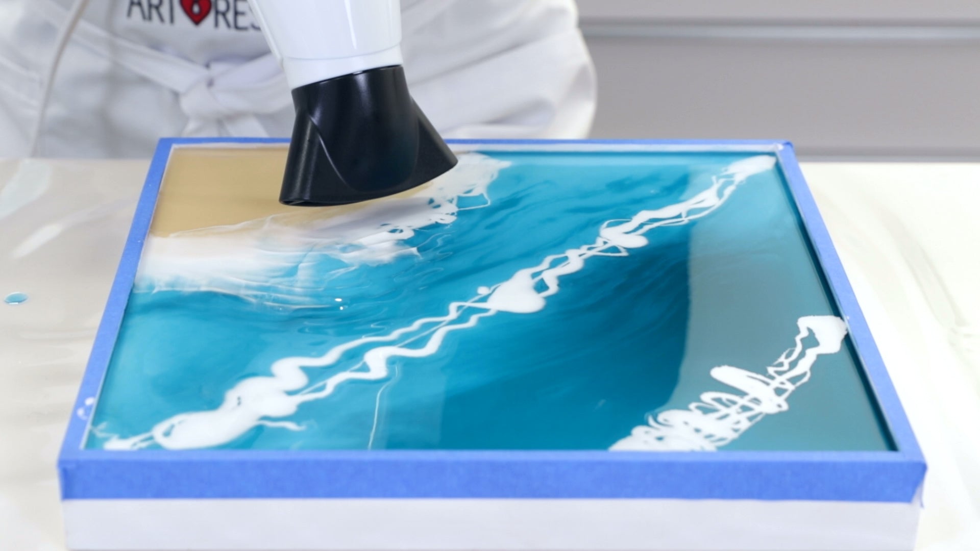 Make Ocean Resin Art - Using the hairdryer, push the white resin layer back and forth