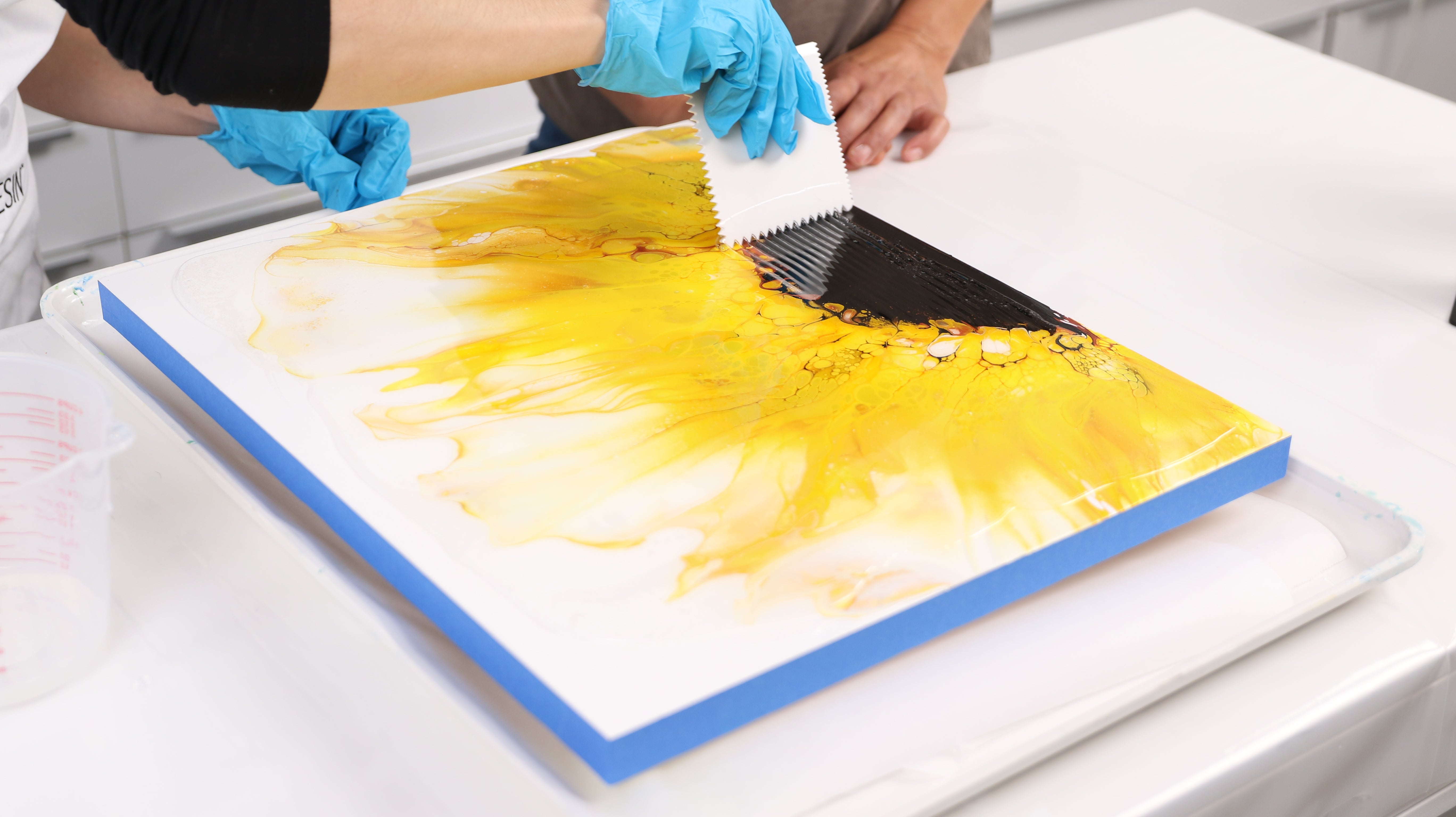 spread resin over surface of painting using spreading tool