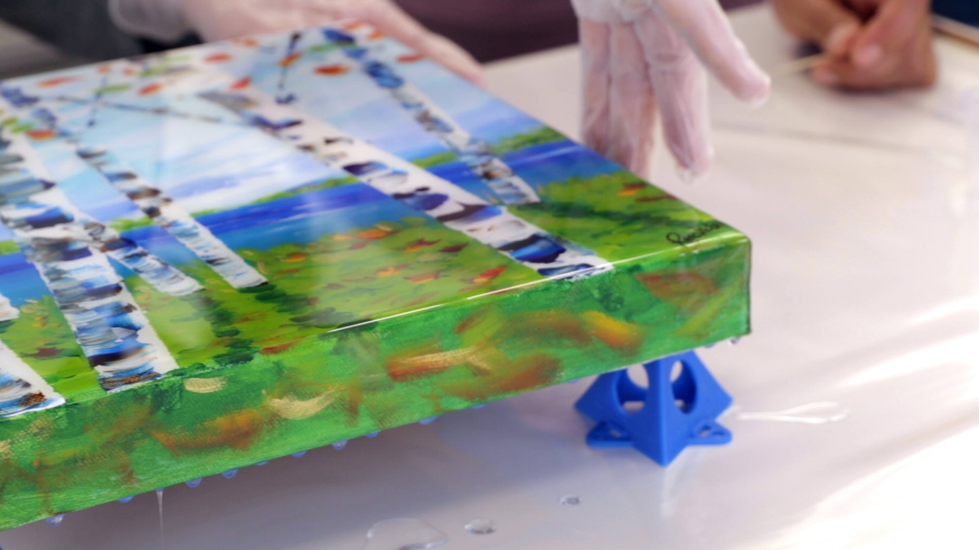 How to Resin a Canvas for Beginners: smooth the resin out, evenly coating each side