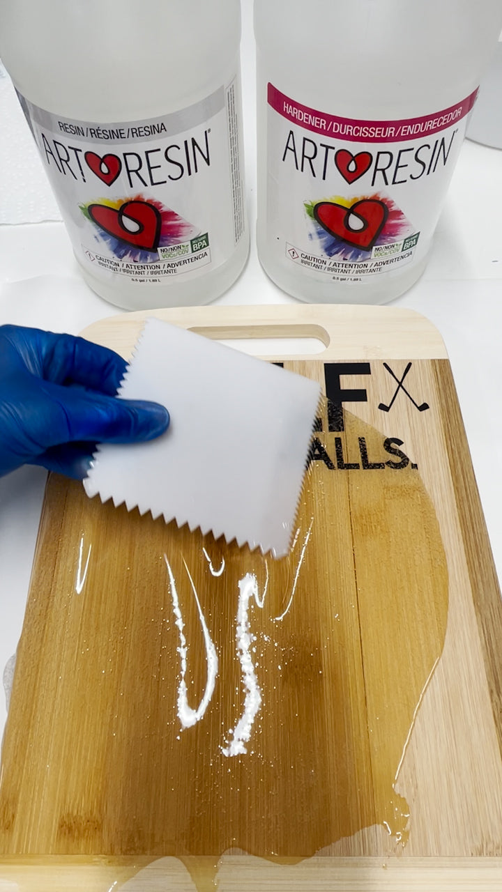 spread epoxy resin across surface of wood board using spreading tool