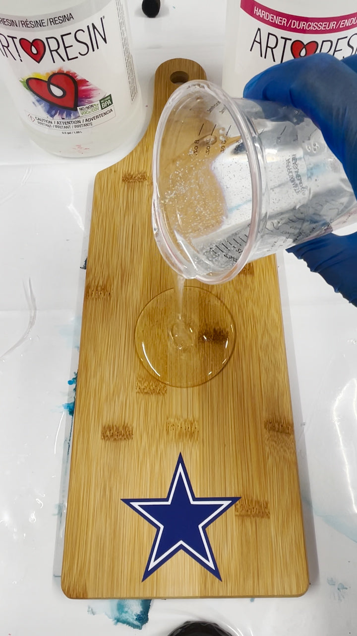 pour mixed resin and hardener into center of wood board over cricut vinyl decal