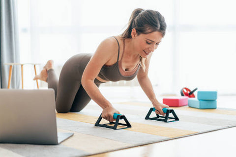 C'est une femme qui fait des excercices de sport muscu, fitness, elle est sur le sol sur un tapis de sport en tenue de sport et fais ce qu'on appelle en muscu "push up"