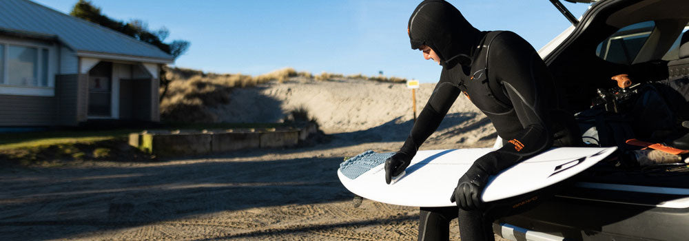 Surfer wearing Cyclone Zipper Free Wetsuit Waxing his Surfboard