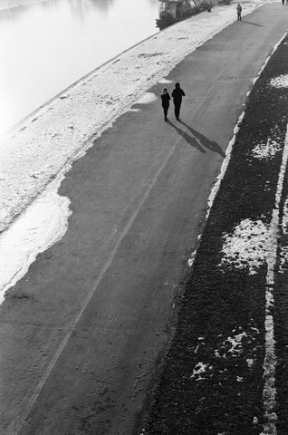 A high angle view of a silhouetted couple walking along a lake
