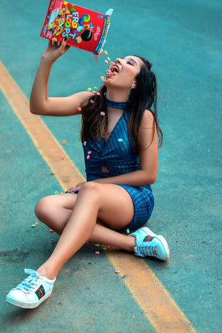 A woman sitting in the road pouring cereal into her mouth