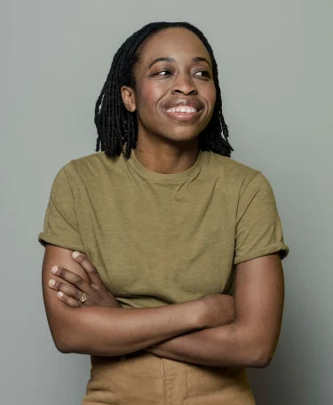 Person smiling, wearing a khaki shirt, arms crossed.