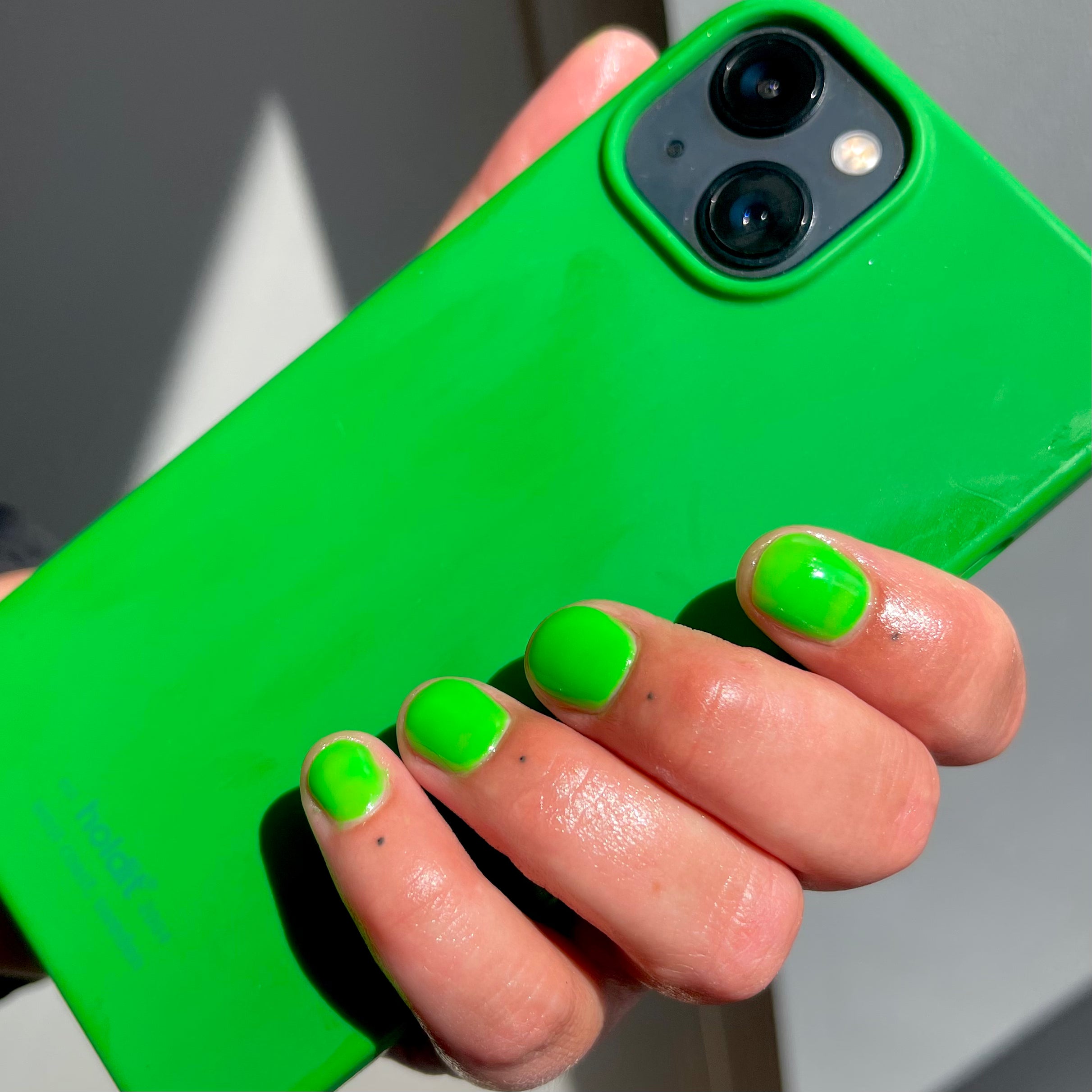 Green gel polish nails holding a phone with green phonecover