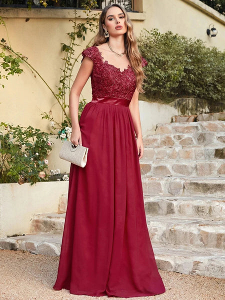 a woman posing in a cap sleeve burgundy long dress