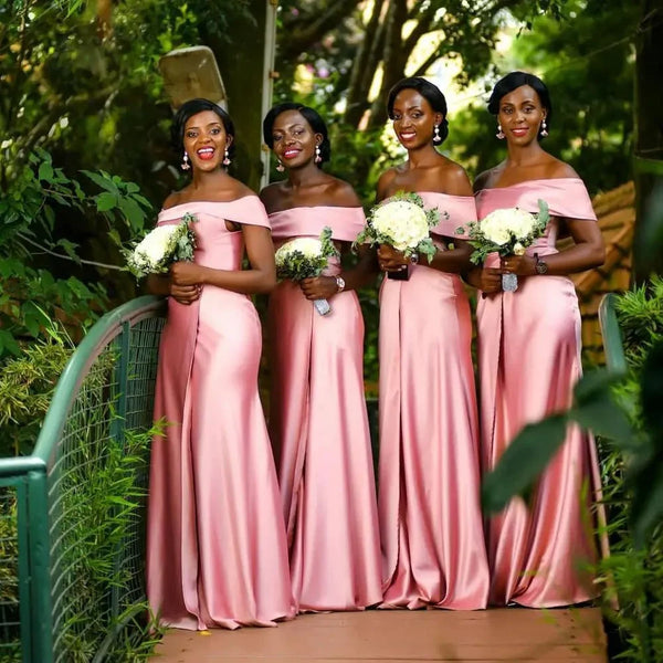 four black women posing in a long pink off the shoulder dresses