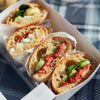 Ciabatta-Sandwiches in weißer Box auf Picknickdecke
