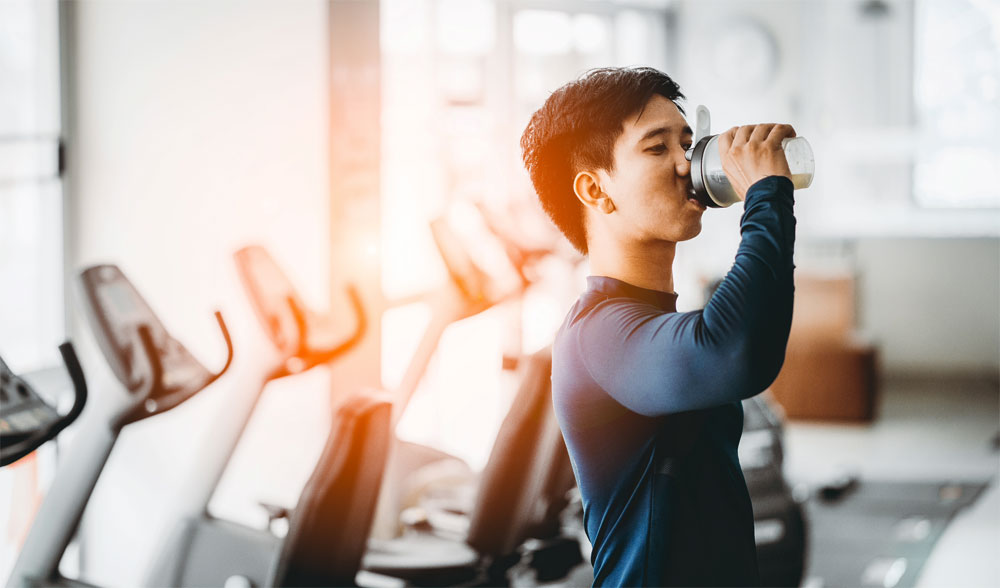 fitness enthusiast drinking protein supplement shake in gym setting