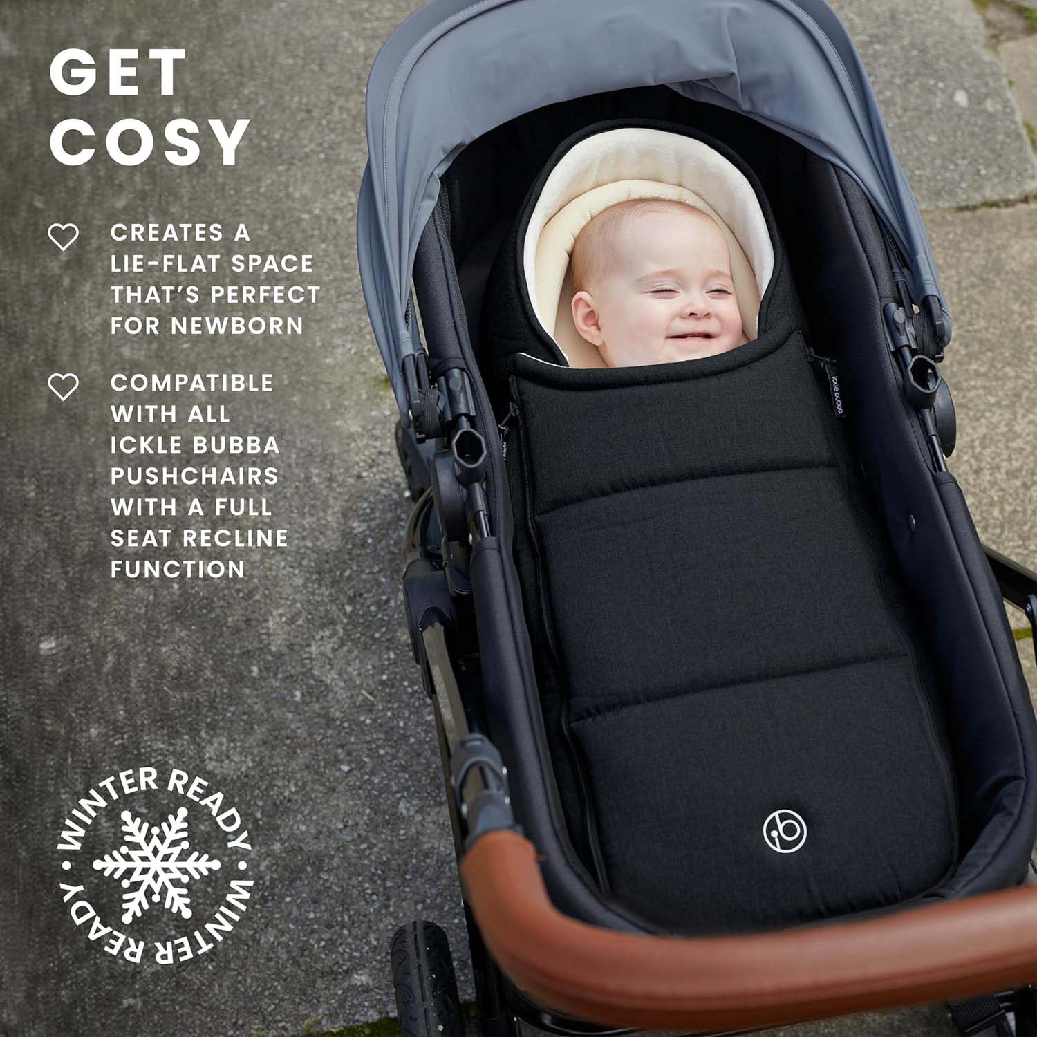 A baby smiling while sleeping in the Black Newborn Cocoon attached to stroller