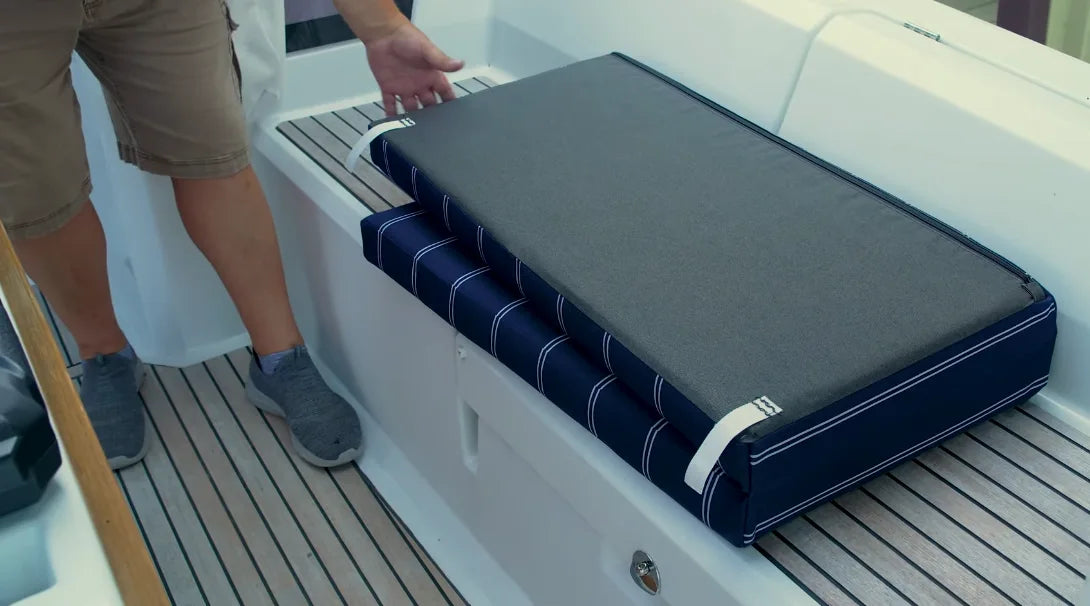 Boat cushion with tie-down straps attached to boat hardware