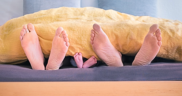 Feet sticking out from under a blanket - mum, dad, baby