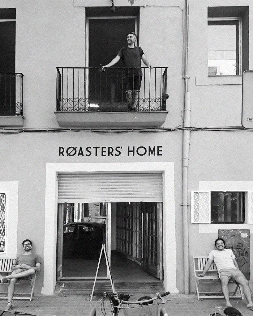 Fachada de Roasters Home, en Pujades 95. Xavier Navas aparece en el piso superior, Jordi Mestre en un Banco a la izuierda y Marc Agullé a la derecha. Está en blanco y negro