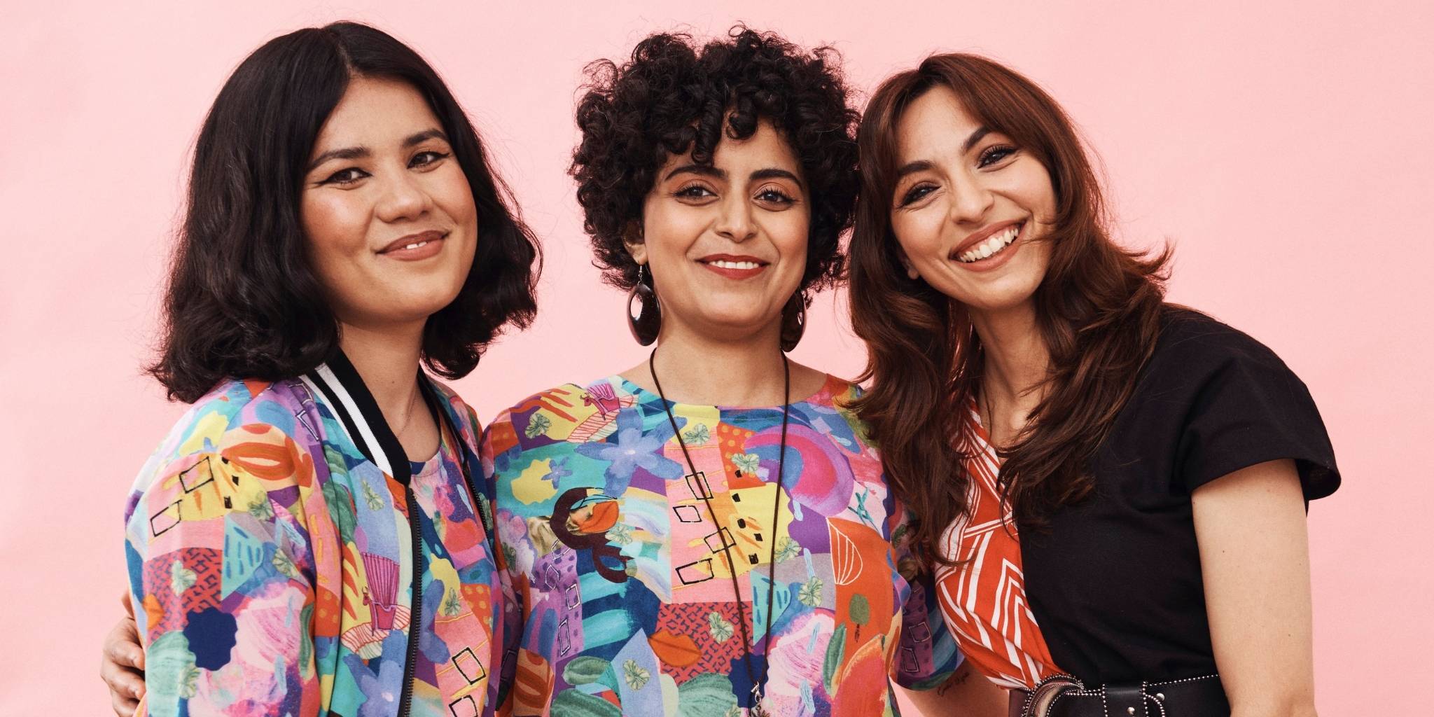 three women posing for a picture wearing colourful clothing and smiling