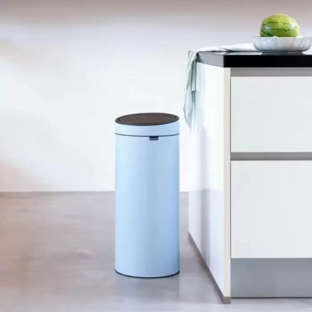 A powder blue Brabantia bin in a white kitchen