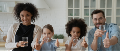 Interracial family drinking water and giving thumbs up