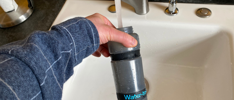 A person is holding a Water-to-Go bottle and pouring tap water into it