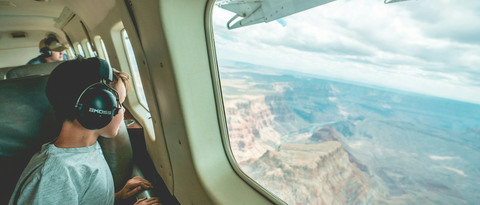 boy on a plane with noise cancelling headphones on looking at the window