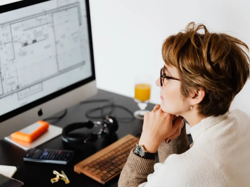 Serious Woman Reading Information On Computer Monitor 