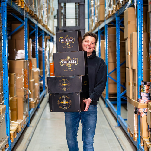 Employee holding boxes of whiskey decanters in warehouse