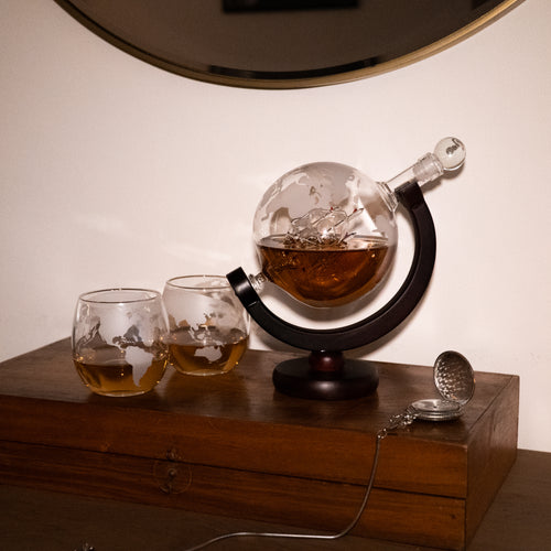Globe whiskey decanter on table with two glasses