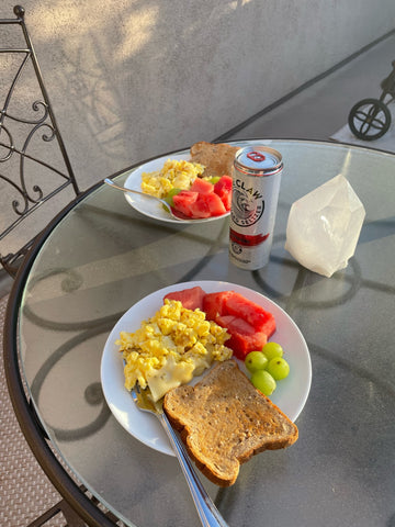 eggs toast and fruit on plate on table outside
