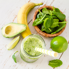 Glass of green smoothie with avocado lime and spinach