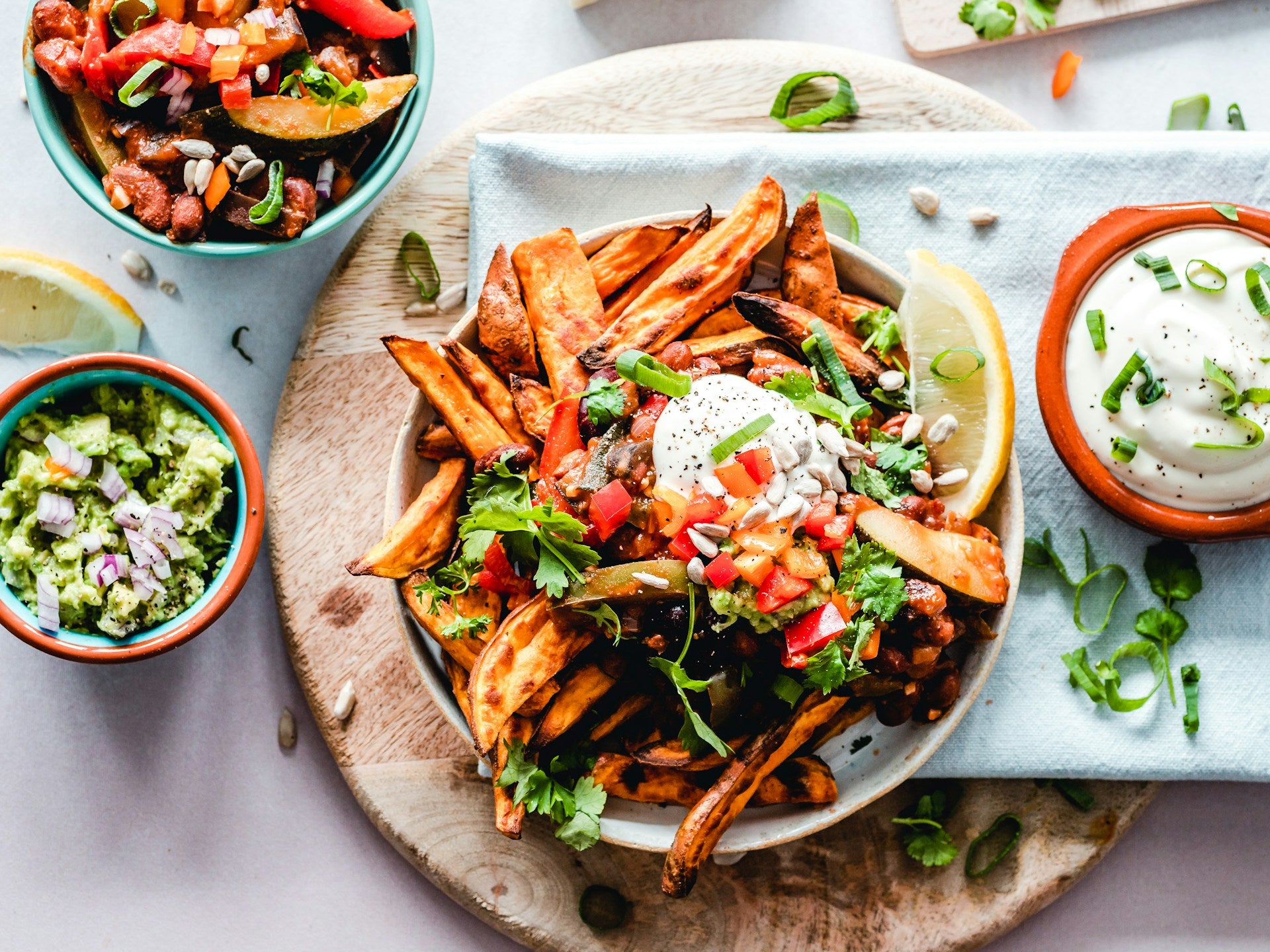 A vibrant flatlay image of a variety of plant-based dishes such as sweet potato fries, guacamole, and more