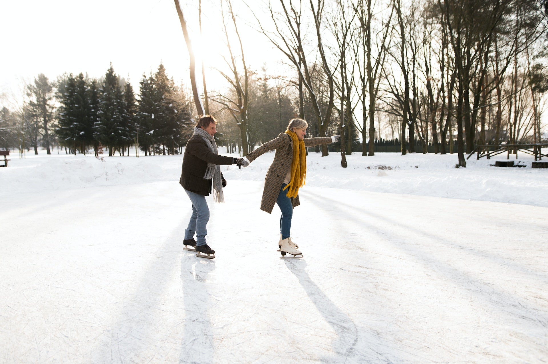A man and a woman ice skating on a pond outdoors