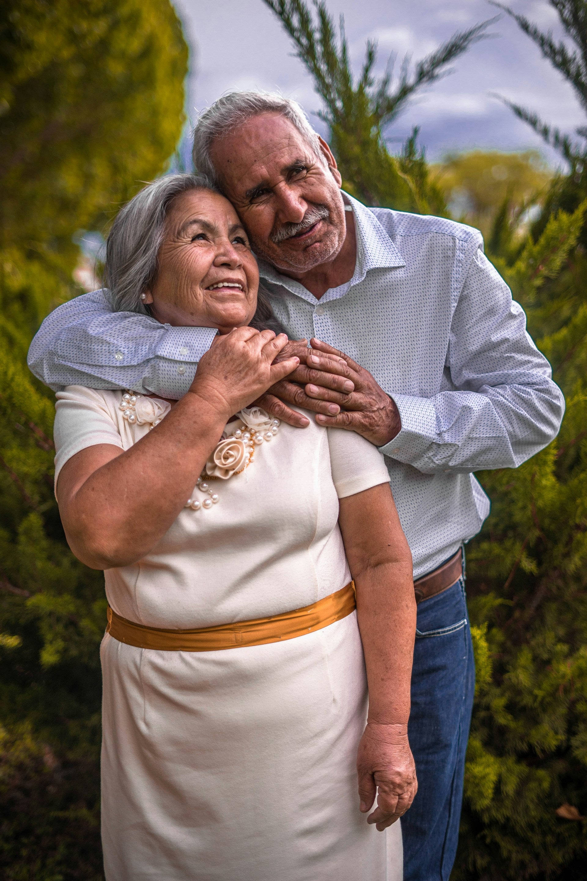 A senior couple holding each other gently while smiling and facing the camera