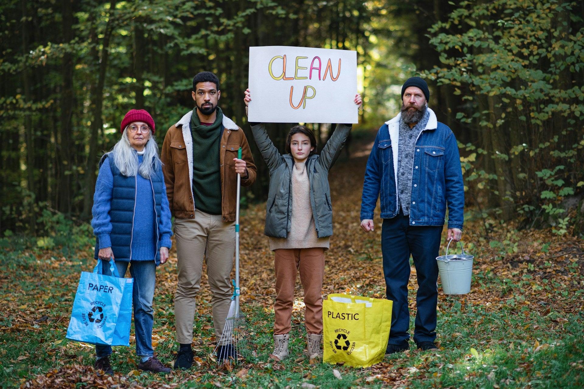 A diverse group of people working together to do a trash cleanup in a forest