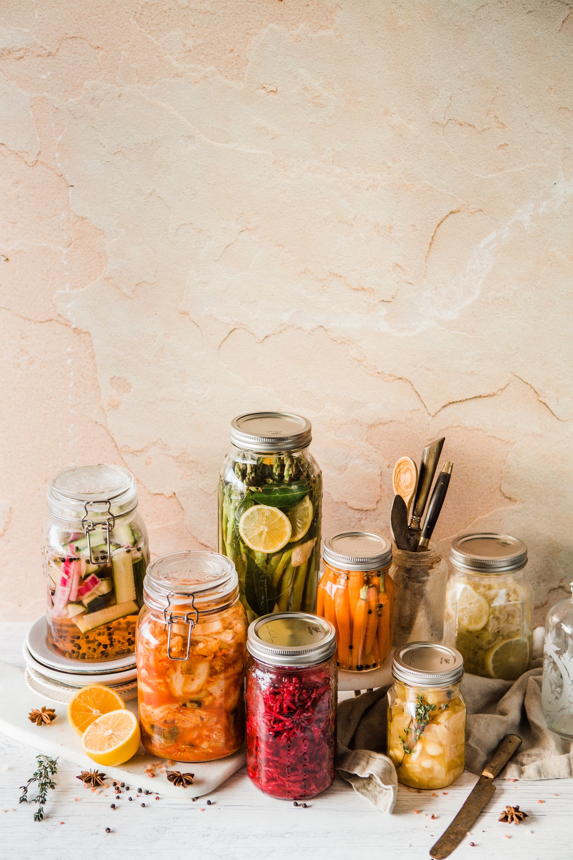 A variety of fermented foods in Mason jars set in front of a beige background