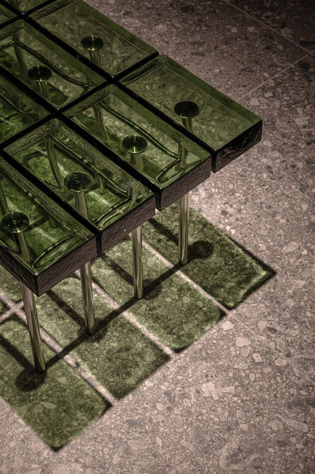 Green glass bricks are joined together to form a table.